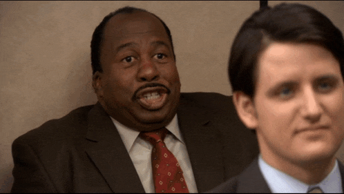 a man in a suit and tie stands next to another man in a blue shirt