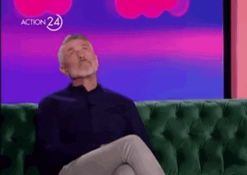 a man is sitting on a green couch with his eyes closed and his mouth open .