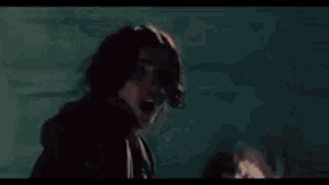 a man is laying on the floor in a dark room with a woman standing behind him .