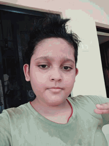 a young boy wearing a green shirt with a red stripe on the sleeve