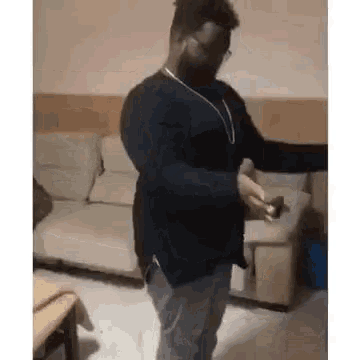 a man is dancing in a living room while holding a cell phone .