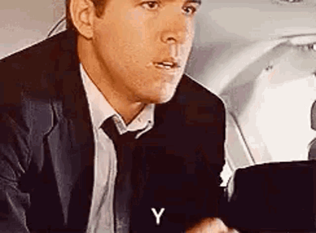 a man in a suit and tie is sitting on a plane .