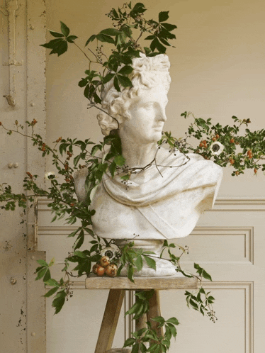 a statue of a man is surrounded by leaves and fruit