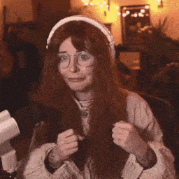 a woman wearing headphones and glasses is sitting in front of a microphone and smiling