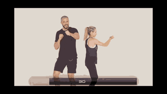 a man and a woman are dancing in front of a white wall with the number 30 on the bottom of the screen