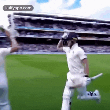 a man in a white shirt is running on a cricket field .