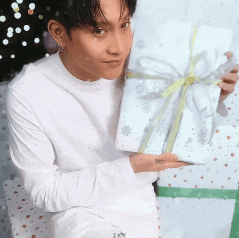 a man in a white shirt is holding a gift with a yellow bow
