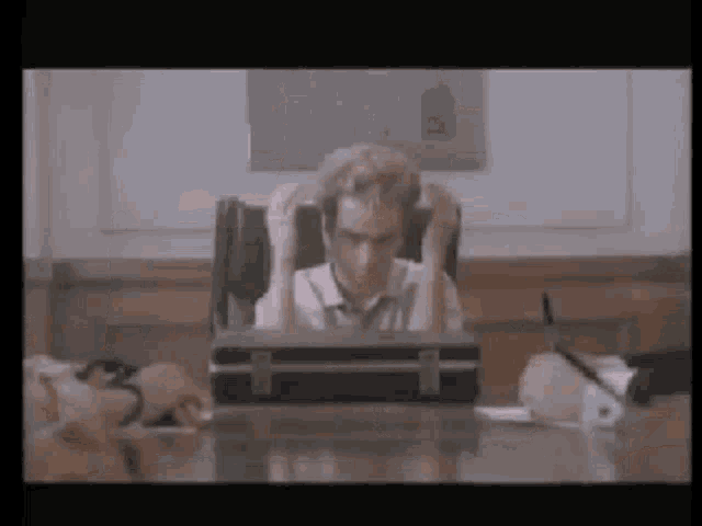 a man sitting at a desk with a briefcase in front of him