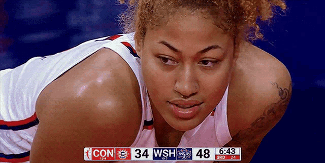 a female basketball player looks down at the scoreboard which says 34 wsh 48