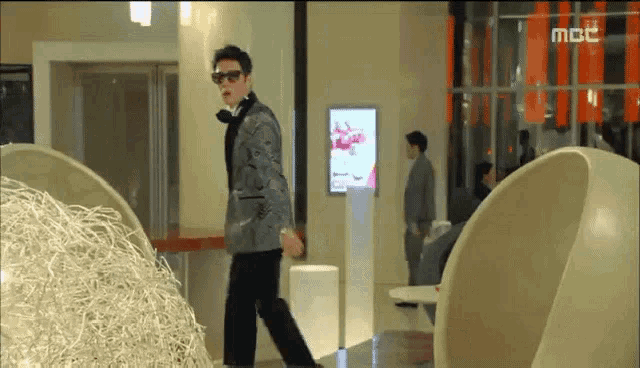 a man in a suit and tie is walking in a room with a mbc logo on the bottom