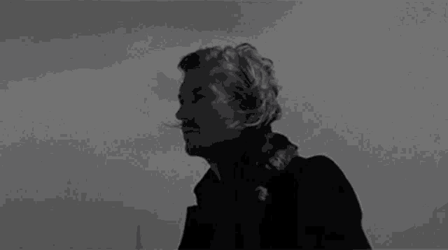 a black and white photo of a man standing in the wind