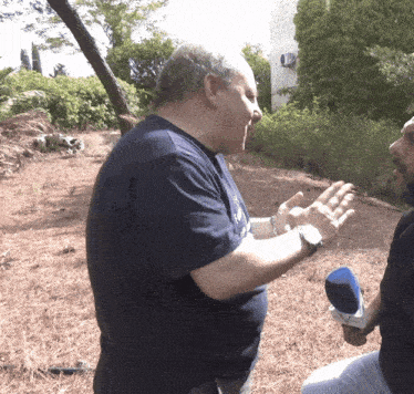 a man in a blue shirt is talking to another man in a black shirt