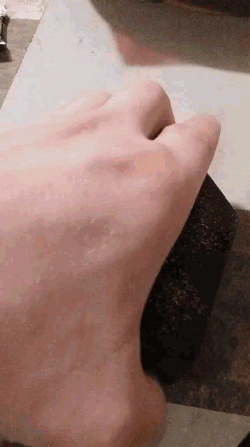 a close up of a person 's hand on a cutting board