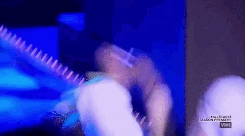 a man is playing a guitar in a dark room with a blue light behind him .