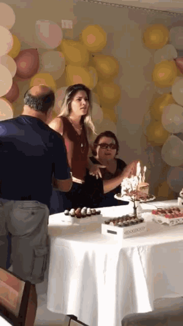 a woman blowing out candles on a cake with a monopoly board in the background