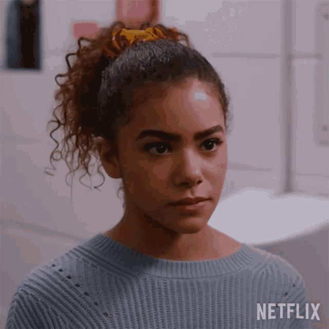 a girl with curly hair is wearing a blue sweater and a netflix logo