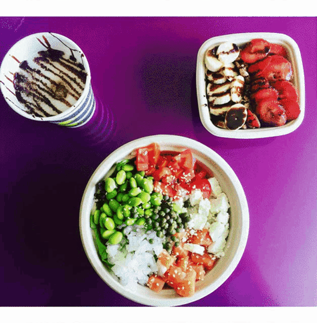 three bowls of food are on a purple table with a cup of chocolate sauce