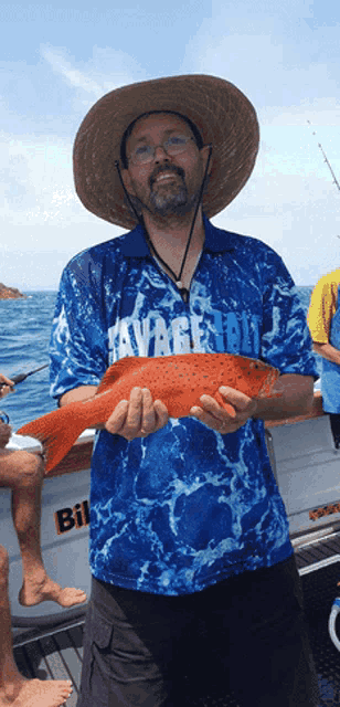 a man holding a fish wearing a shirt that says savage tail
