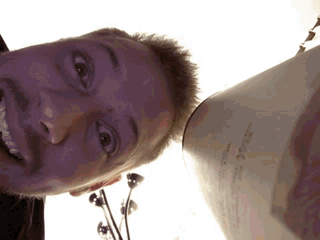 a man 's face is shown with a lamp in the background and a piece of paper on the floor