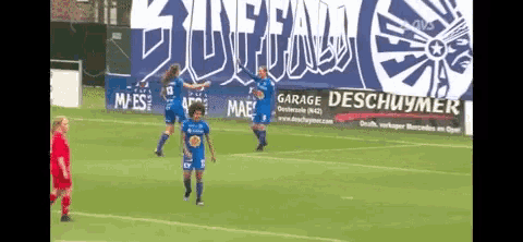a group of soccer players on a field in front of a garage deschuymer sign