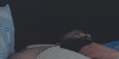 a person is laying on a bed with their legs crossed and their hands on their knees .