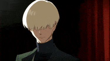 a man in a suit and turtleneck adjusts his hair in front of a red curtain
