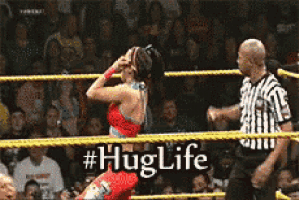 a woman is dancing in a wrestling ring while a referee looks on