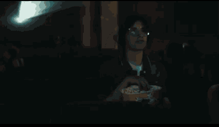 a man is sitting in a theater eating popcorn