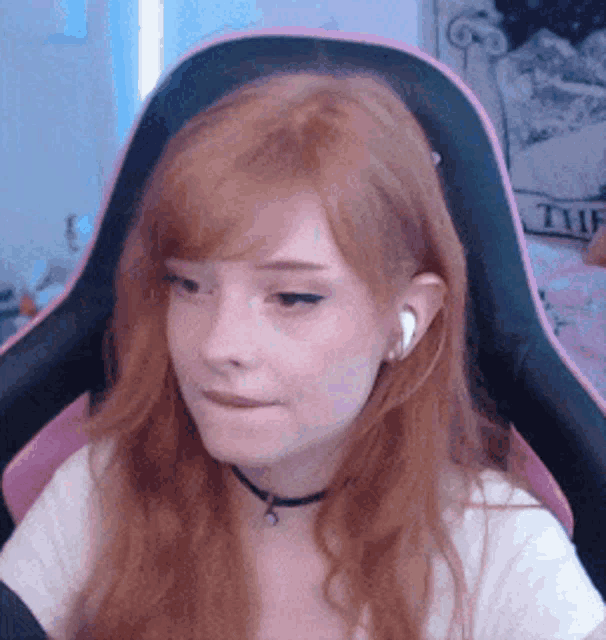 a girl with red hair is sitting in a chair wearing headphones .