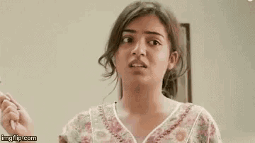a woman in a floral shirt is making a funny face while standing in front of a wall .