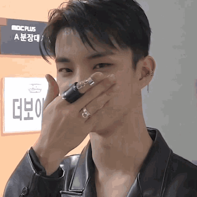 a man covering his mouth in front of a sign that says mbc plus a