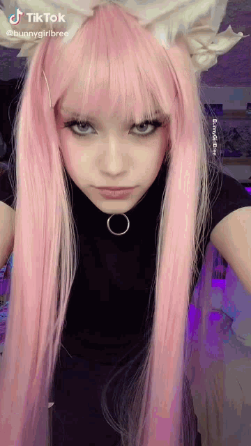 a girl with long pink hair is wearing a cat ear headband and a choker .