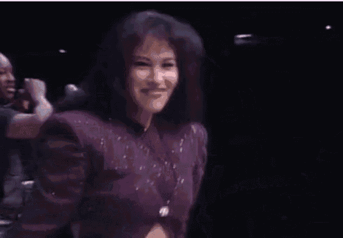 a woman in a purple dress is dancing on a stage in front of a microphone .
