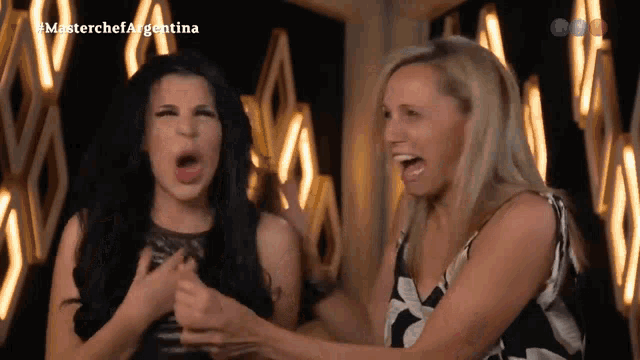 two women are making funny faces in front of a masterchef argentina sign