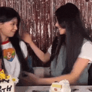 two women are standing next to each other at a birthday party .