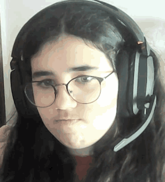 a young girl wearing glasses and headphones is making a funny face .