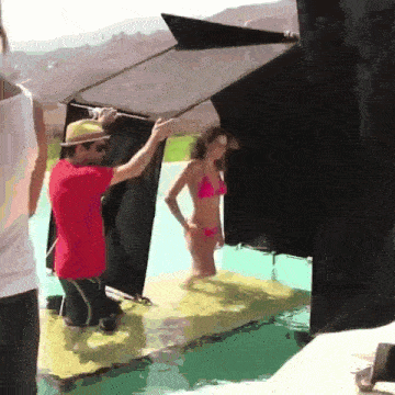 a woman in a pink bikini is standing on a raft in a pool