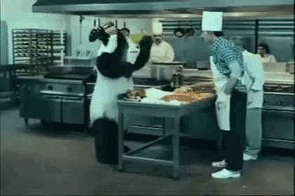 a panda bear is standing next to a table in a kitchen .