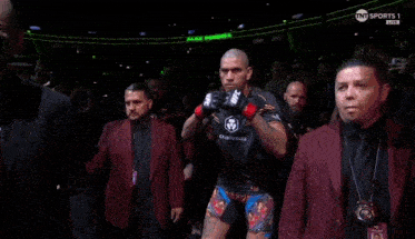 a man wearing a pair of ufc boxing gloves stands in a crowd