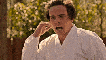 a man wearing a white karate uniform is making a funny face