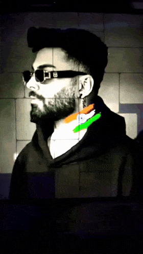a man with a beard wearing sunglasses and a black hoodie with the letter b on the front