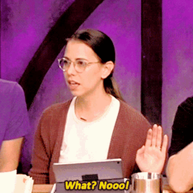 a woman sitting at a table with a tablet and says what nooo!