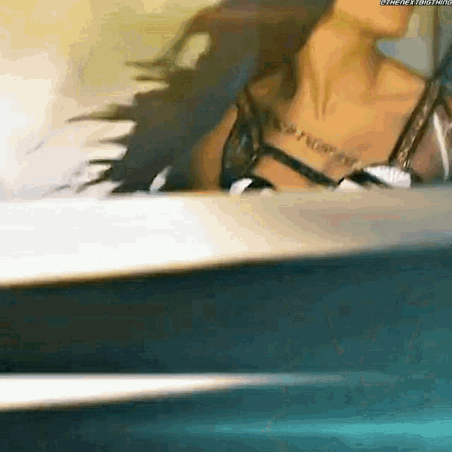 a woman in a bikini is standing in front of a mirror with her hair blowing in the wind .