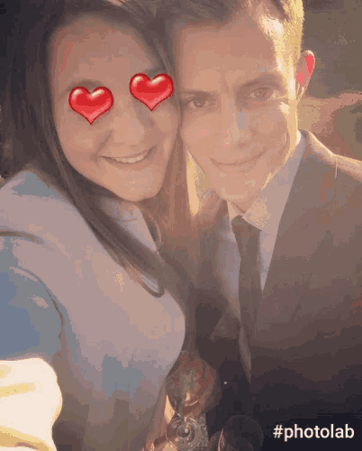 a man and a woman are posing for a photo with hearts in their eyes