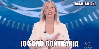 a woman in a white suit stands in front of a clock and says io sono contraria