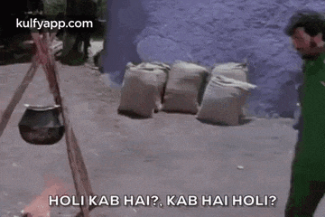 a man in a green shirt is standing in front of a pile of bags and a pot .