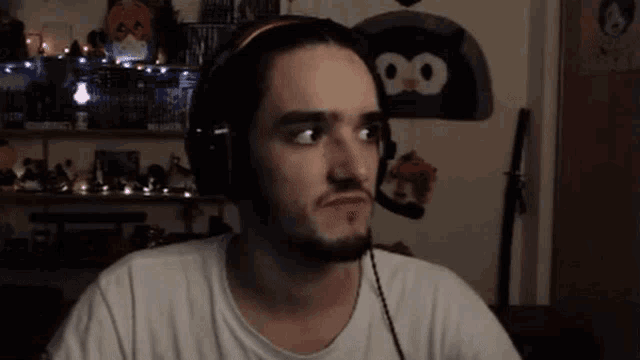 a man wearing headphones looks at the camera in front of a wall with a penguin on it