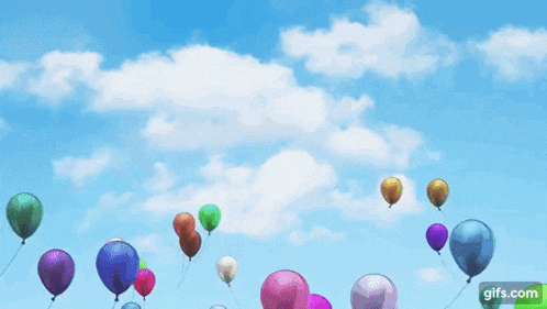 a bunch of balloons are flying in the sky .