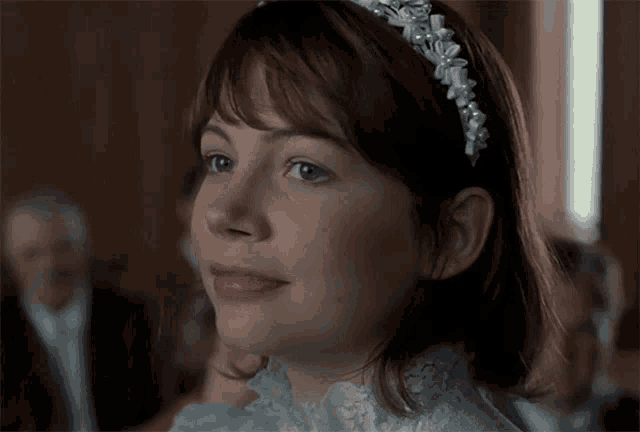 a woman wearing a white dress and a headband with pearls on it
