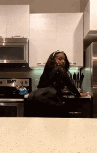 a woman is standing in a kitchen wearing sunglasses .